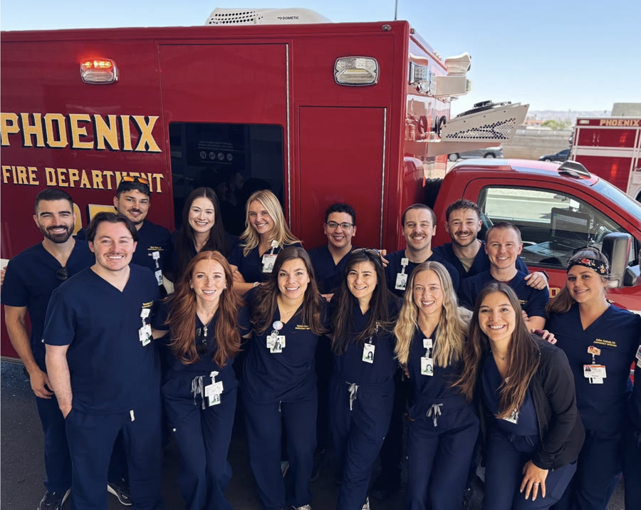 The crew in scrubs in front of a Phoenix Fire Department ambulance